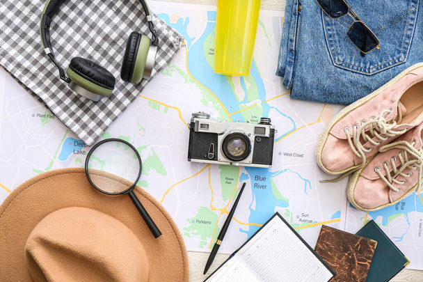 Accessories for travelling with city map on white wooden background - 写真・画像