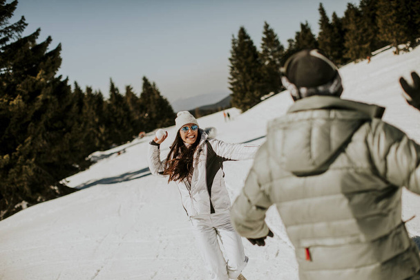 Young couple having snowball fight at a sunny day on the mountain - Foto, Imagem