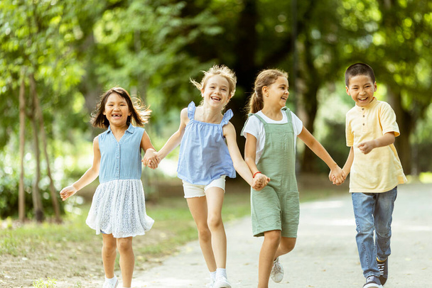 Group of cute asian and caucasian kids having fun in the park - Photo, image