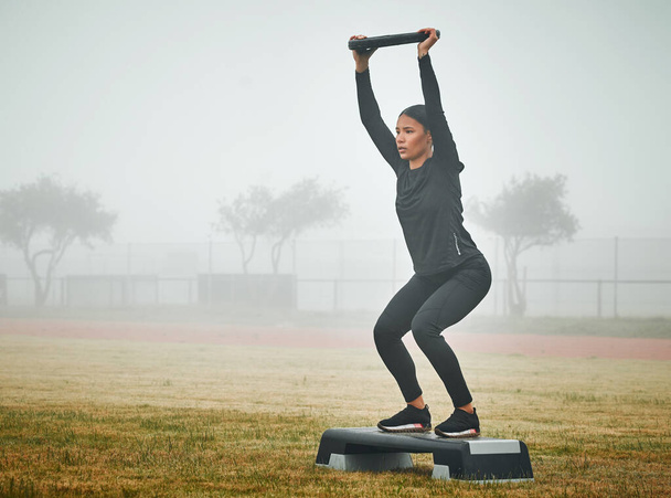 Es wird schwer, aber denken Sie daran, wie stark Sie sind. eine sportliche junge Frau, die auf einer Stufe mit einer Hantelscheibe im Freien trainiert - Foto, Bild