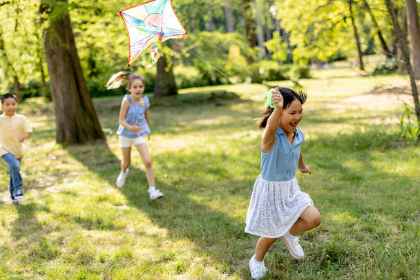 Cute little girl running happily with a kite in the park - Fotografie, Obrázek