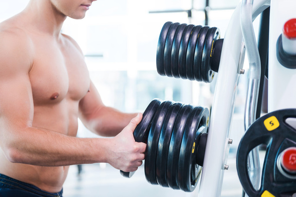 Muscular man choosing weight for exercising - 写真・画像