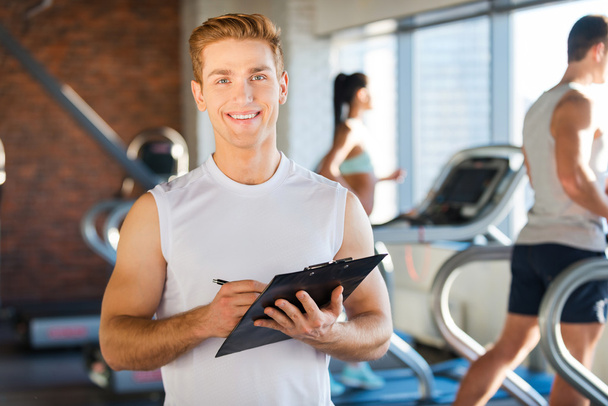 Man holding clipboard while people running on treadmill - Photo, Image
