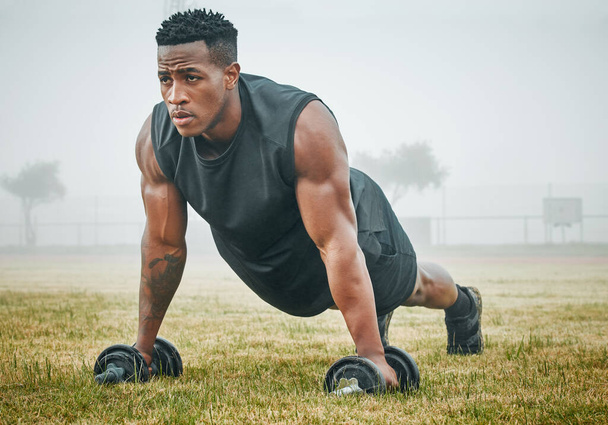 Stay on the rise. a muscular young man exercising with dumbbells outdoors - Photo, Image