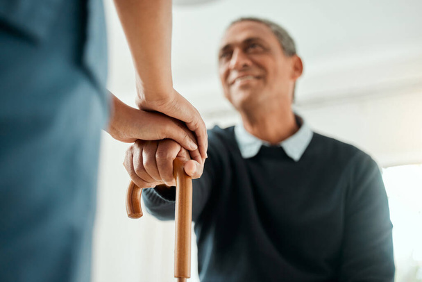 We get up every time. a nurse helping an older man stand up and use his walking stick - Foto, Bild