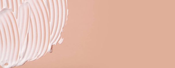 Nahaufnahme Creme Feuchtigkeitscreme Schmierfilm wellige Textur auf farbigem Hintergrund mit Kopierraum horizontales Format. Schönheitsprodukt zur Hautpflege. - Foto, Bild