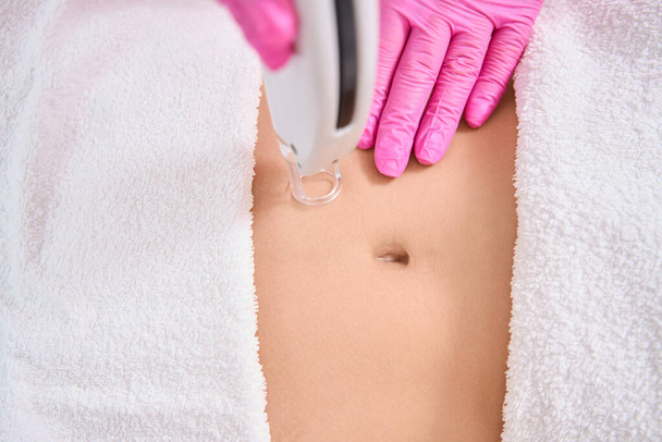 Lady is undergoing a professional procedure for grinding the top layer of skin on her stomach - Photo, image