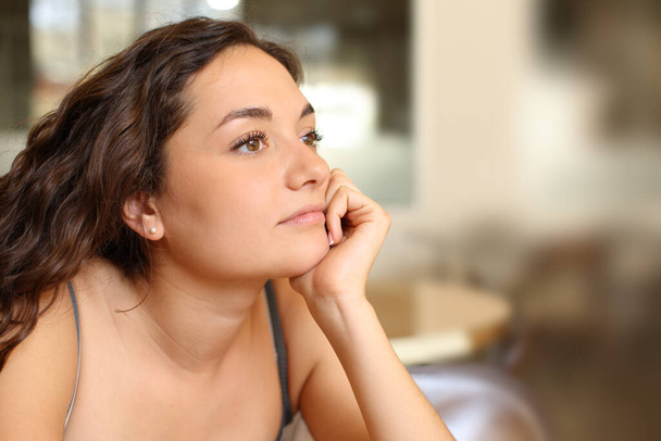 Pensive woman looking away distracted sitting in a coffee shop - Фото, зображення