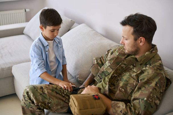 Child applying tourniquet as part of his first aid military training by his father - Foto, immagini