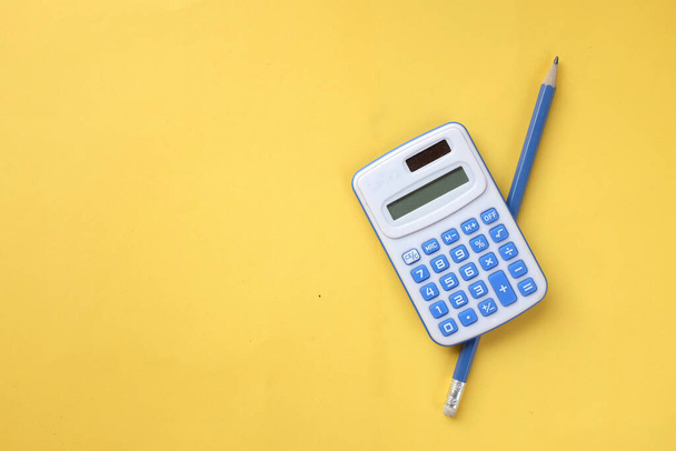 copy space  pencil and blue Calculator isolate on a yellow background - Photo, image