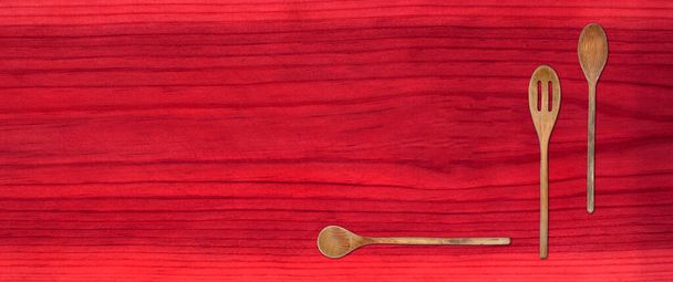 Vista superior del conjunto de cucharas de madera de cocina sobre fondo de mesa rojo - Foto, Imagen