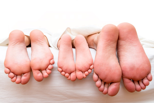 pieds des parents et de l'enfant sur le lit gros plan
 - Photo, image