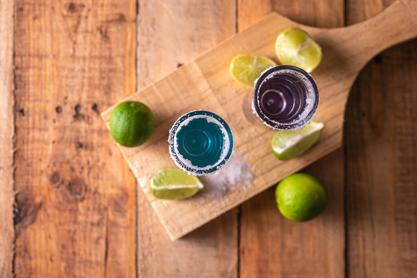 A tequilát tequila pohárban tálalták egy fából készült asztalon. Tequila feles sóval és lime-mal a bárasztalon. - Fotó, kép