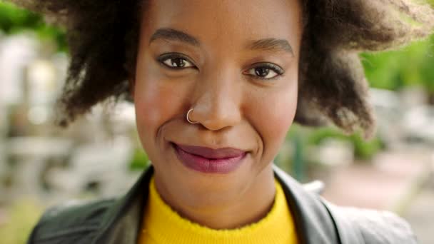 Laughing edgy woman with an afro sightseeing in a city. Closeup portrait, headshot, face of fun, happy tourist standing downtown. Stylish, fashionable woman with red lipstick smiling or enjoying town. - Filmagem, Vídeo