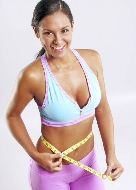 Latin woman holding a measuring belt on her belly after workout. - Photo, Image