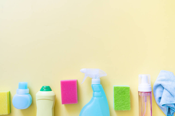Cleaning concept - cleaning supplies on pastel yellow background, top view - 写真・画像