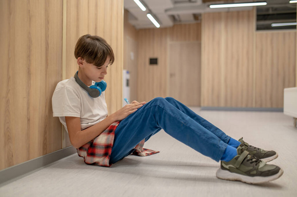 Homework. A boy sitting on the floor and doing his homework - Fotografie, Obrázek