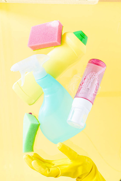 Cleaning concept - levitation of cleaning supplies on pastel yellow background, copy space - 写真・画像