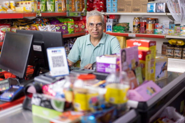 Happy man working as a cashier at supermarket - Foto, imagen