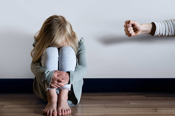 child abuse, violence concept - young girl scared sitting on the floor, parent fist, physical punishment. High quality photo - Valokuva, kuva