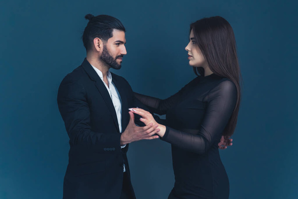 Elegante coppia che si guarda in piedi in posa danza su sfondo blu scuro. Foto di alta qualità - Foto, immagini