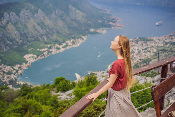 Woman tourist enjoys the view of Kotor. Montenegro. Bay of Kotor, Gulf of Kotor, Boka Kotorska and walled old city. Travel to Montenegro concept. Fortifications of Kotor is on UNESCO World Heritage. - Fotografie, Obrázek