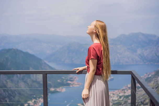 Woman tourist enjoys the view of Kotor. Montenegro. Bay of Kotor, Gulf of Kotor, Boka Kotorska and walled old city. Travel to Montenegro concept. Fortifications of Kotor is on UNESCO World Heritage. - Фото, зображення