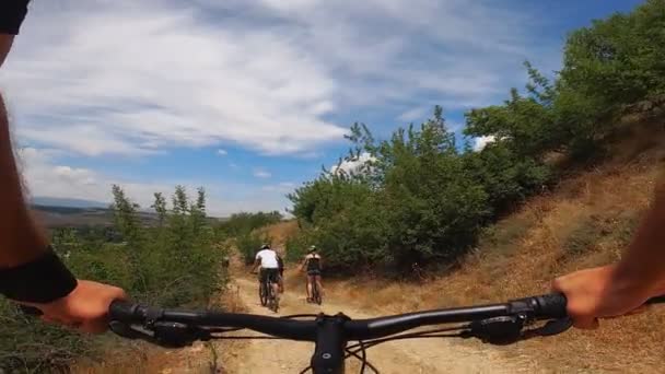 Emberek csoportja kerékpározás együtt a hegyi úton nyáron, első személy nézet, lassított felvétel - Felvétel, videó