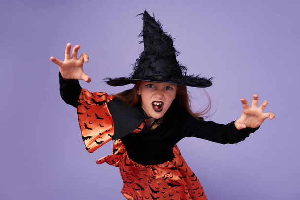 Funny children in carnival costumes in honor of Halloween on a purple background. - Photo, image