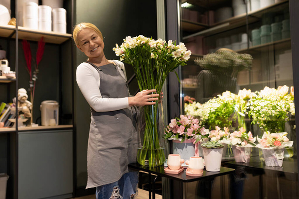 Elinde taze çiçekler tutan çiçekçi bir butiğin çalışanı.. - Fotoğraf, Görsel