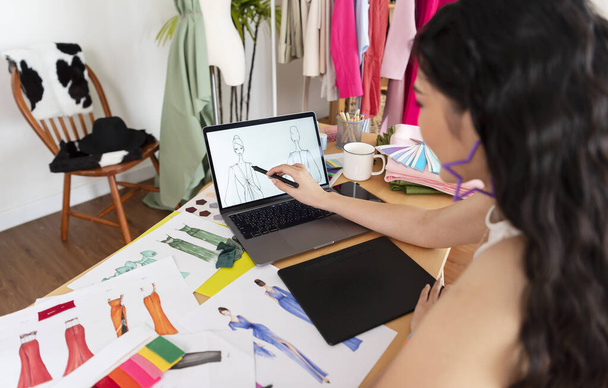 Mooie Aziatische Fashion ontwerper tekening schetsen voor nieuwe collectie op computer laptop. Ontwerper creatieve workshop studio. - Foto, afbeelding