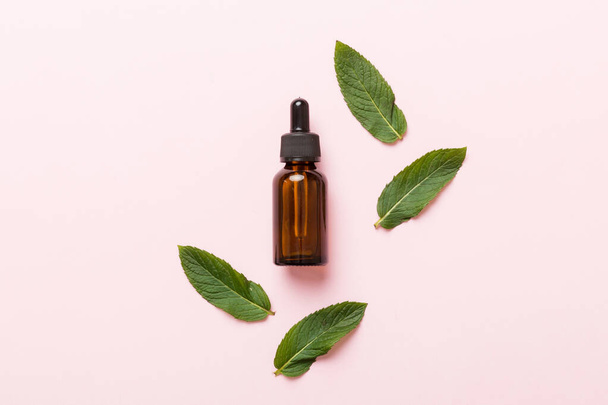 Natural Mint Essential Oil in a Glass Bottle. organic cosmetics with herbal extracts of mint on colored background. - Fotografie, Obrázek