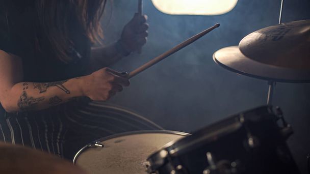 Enthusiastic female drummer plays a drum kit holding drumstick in tattooed hands - Foto, Imagem