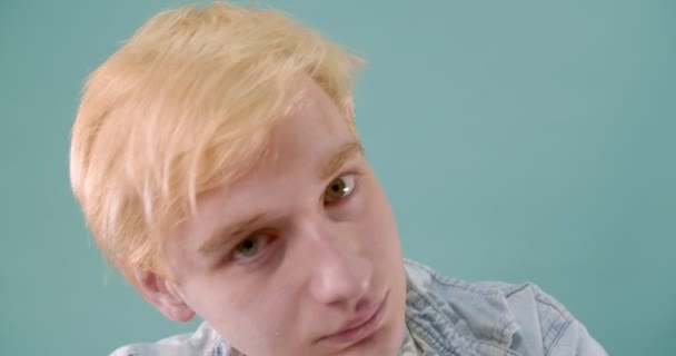 Blonde boy is chewing the candy while making crazy faces with his tongue out - Materiał filmowy, wideo