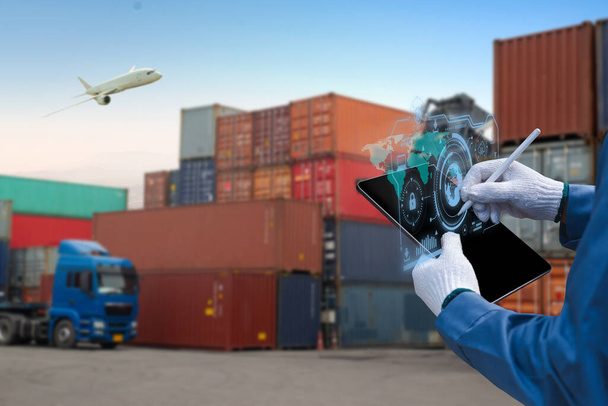 Ручной техник нажимает на карту мира с цифровым планшетом, грузовой корабль промышленных контейнеров в сумерках для логистического импорта - Фото, изображение