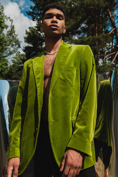 low angle view of african american man in green blazer near flexible mirror in park - Fotografie, Obrázek