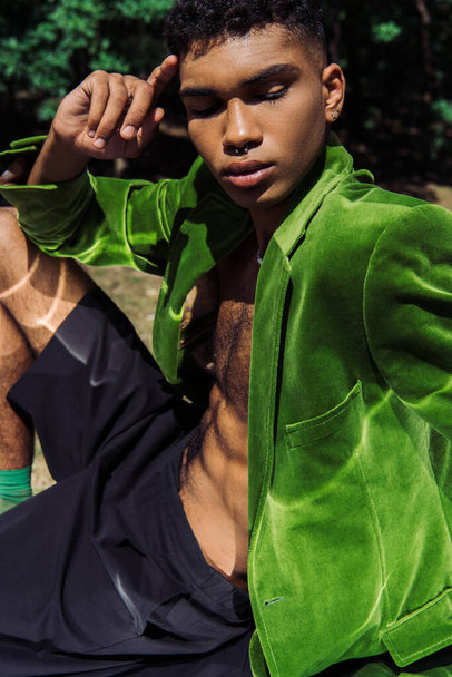 fashionable african american man in green blazer and black shorts sitting outdoors - Foto, imagen