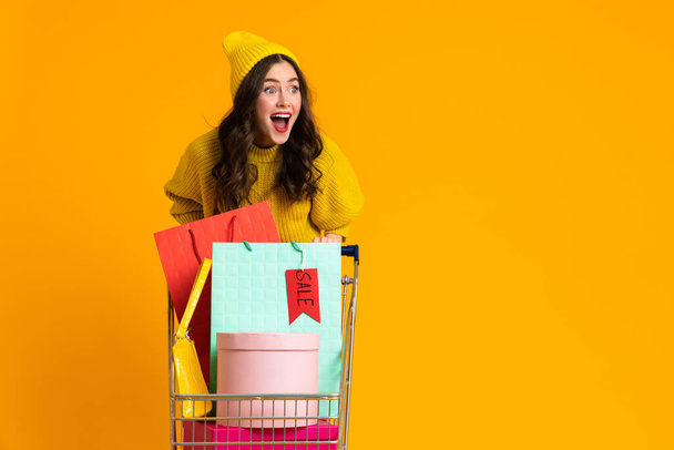 Innoissaan nainen huutaa poseeratessaan ostoskorin eristetty keltaisella taustalla - Valokuva, kuva