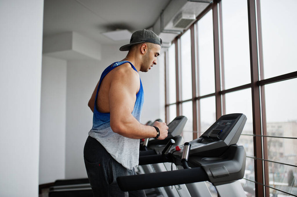 Fit and muscular arabian man running on treadmill in gym. - Фото, зображення