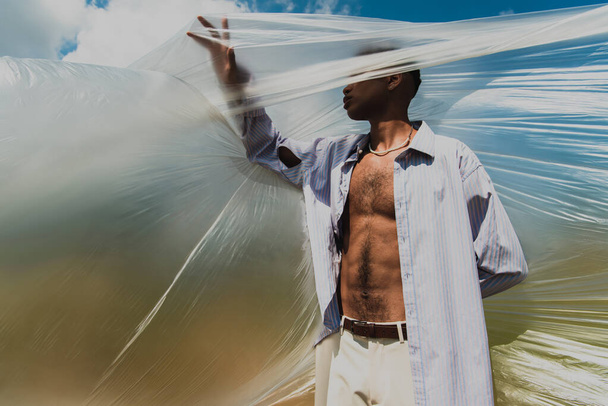 african american man in blue shirt posing near cellophane film - Photo, image