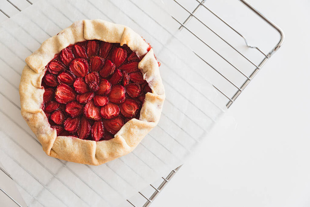 Homemade strawberry galette pie on baking sheet on white table. Top view - Фото, изображение