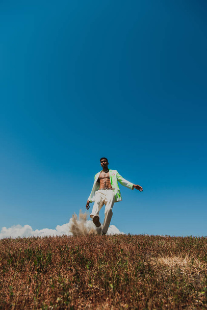 young african american man in white trousers under blue sky in meadow - Foto, Bild