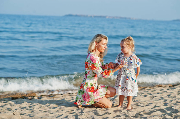 Mother and beautiful daughter having fun on the beach. Portrait of happy woman with cute little girl on vacation.  - Foto, afbeelding