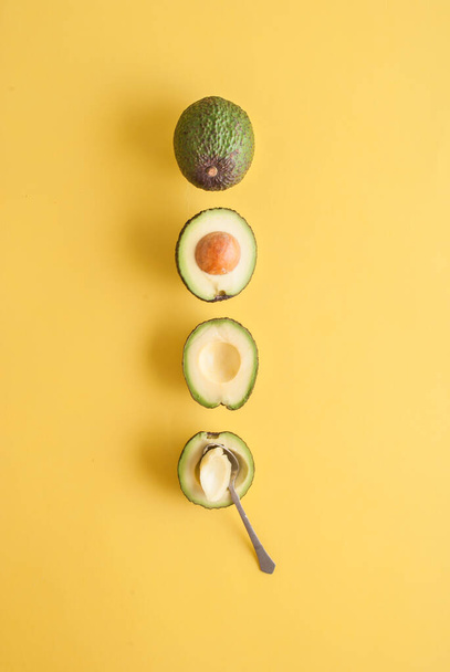 studio shot of avocadoes with spoon isolated on yellow background  - Photo, Image