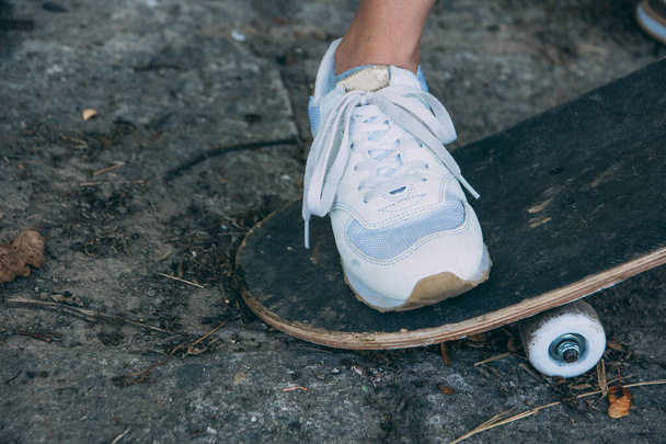 a woman leg with white sports shoes on a skater board - Fotoğraf, Görsel