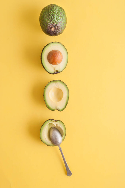 студийный кадр авокадо с ложкой на желтом фоне  - Фото, изображение