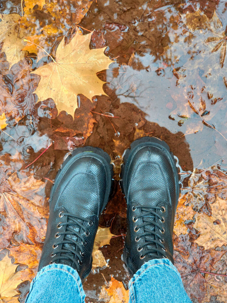 ноги в сапогах на мокрых осенних листьях - Фото, изображение