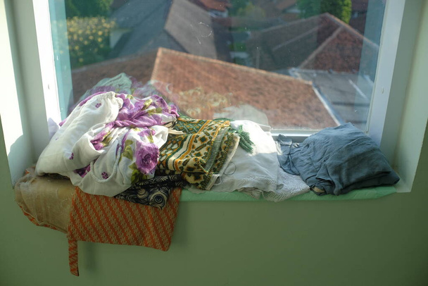 Mukena, Muslim women's clothing for prayer and prayer mats are placed near the window of the prayer room. - 写真・画像