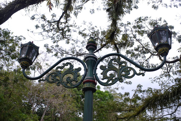 Hoch aufragende dekorative Gartenlichter stehen in einem wunderschönen öffentlichen Park voller Bäume. - Foto, Bild