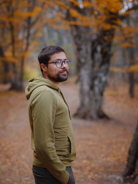 Young handsome man posing in autumn forest on road. young hipster guy with backpack , traveller standing in woods, Hiking, Forest, Journey, active healthy lifestyle, adventure, vacation concept. - Photo, Image